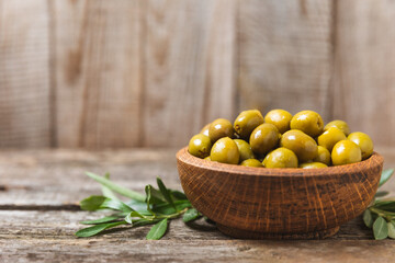 Green olives on a white wooden background. Various types of olives in bowls and olive oil with fresh olive leaves. Copy space. Place for text. Mediterranean food. Vegan.