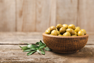 Green olives on a white wooden background. Various types of olives in bowls and olive oil with fresh olive leaves. Copy space. Place for text. Mediterranean food. Vegan.