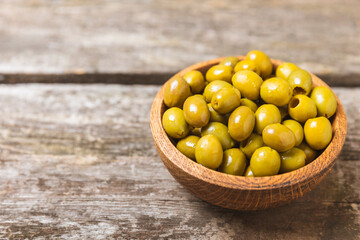 Green olives on a white wooden background. Various types of olives in bowls and olive oil with fresh olive leaves. Copy space. Place for text. Mediterranean food. Vegan.