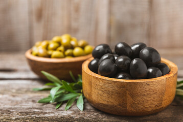 Green and black olives on a white wooden background. Various types of olives in bowls and olive oil with fresh olive leaves. Copy space. Place for text. Mediterranean food. Vegan.