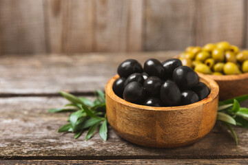 Green and black olives on a white wooden background. Various types of olives in bowls and olive oil with fresh olive leaves. Copy space. Place for text. Mediterranean food. Vegan.