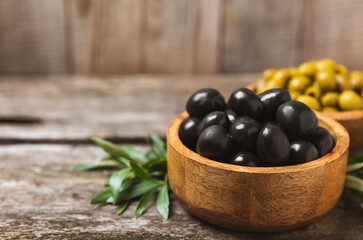Green and black olives on a white wooden background. Various types of olives in bowls and olive oil with fresh olive leaves. Copy space. Place for text. Mediterranean food. Vegan.