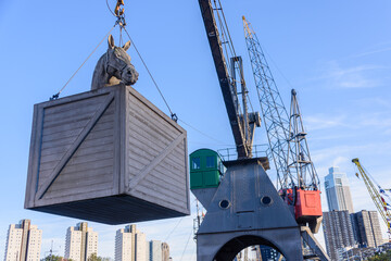Crane holds a model of a crate containing a horse at the Port of Rotterdam, Netherlands