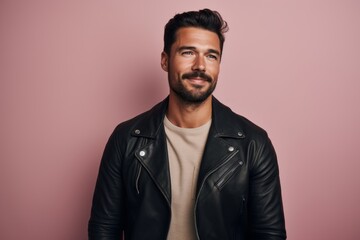 Obraz premium Portrait of a content man in his 30s sporting a classic leather jacket against a solid pastel color wall. AI Generation