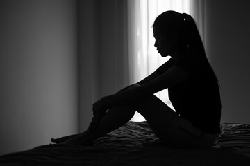 Silhouette of depressed woman sitting in bedroom Beset by health problems accumulated stress...