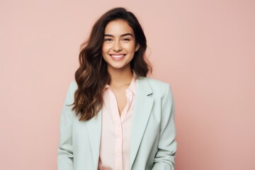 Fototapeta premium Portrait of a grinning woman in her 20s dressed in a stylish blazer against a solid pastel color wall. AI Generation