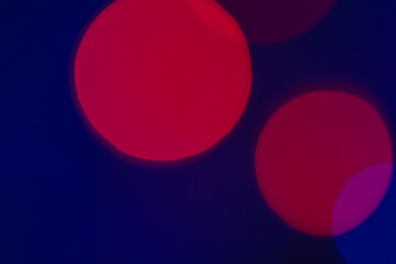 Red defocused light circles on a dark background with a blue tint. Abstract background of multi-colored light circles