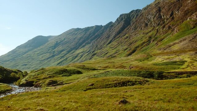Golden hour panning shot of Glen Coe, a glen of volcanic origins, in the Highlands of Scotland, UK, home to the clan McDonald