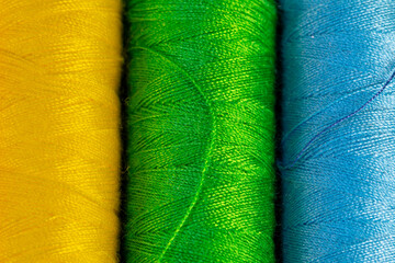 Spools of colored threads. Spools of yellow, green and blue thread for sewing