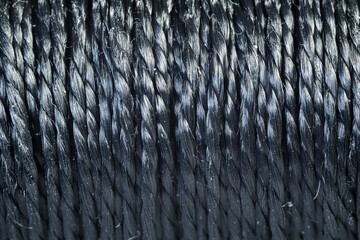 A spool of thick black thread closeup. A skein of black braided thread