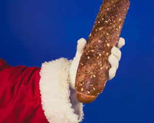 Santa Claus's hand in a white glove holds a bread.