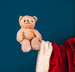 Santa's hand in a white glove holds a teddy bear. A Christmas gift. Concept for child protection. Space for text.