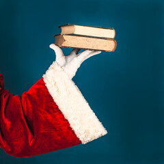 Santa's hand with an two old book on a blue background with copy space.