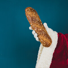 Santa's hand in a white glove holds a whole wheat bread.