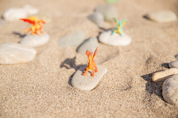 New Year's dragons toy on the beach, child playing in the sand on pebbles