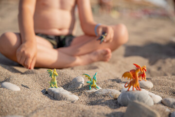 New Year's dragons toy on the beach, child playing in the sand on pebbles