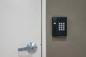 Foto op Canvas The digital locking keypad with number dial that installed on the wall closed to the locked door. Technology device object, close-up. © Nattawit