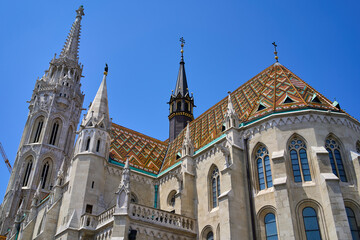 Fototapeta na wymiar Close ups of the decorative roof with orange and green colors, windows and black spire of the 13th-century church Matthias Church in Budapest, Hungary.