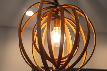 A ceiling lighting bulb glowing in orange warm light, decoration for the cozy style room. Interior...