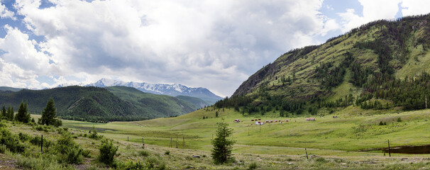 snow peaks behind green mountains under rain clouds