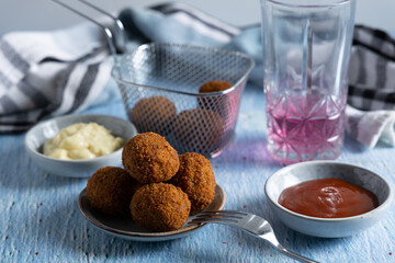 Fried meatballs in a bowl with ketchup on the side.