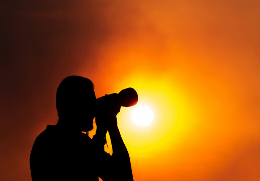 A silhouette of a photographer with a camera at sunset.