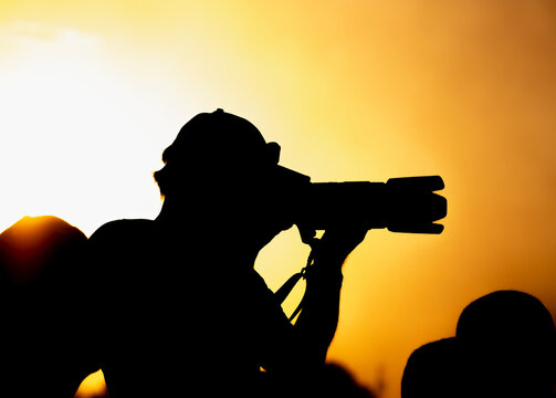 A silhouette of a photographer with a camera at sunset.