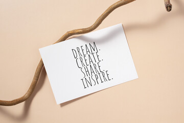 Dream, create, share, inspire words written on card. Invitation card on beige background.