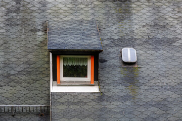 Rectangular mezzanine window on the roof of the house with flexible gray tiles. From the Windows of the world series.