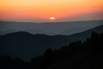 Fototapeta na wymiar hills, forest and the sun setting behind the mountains