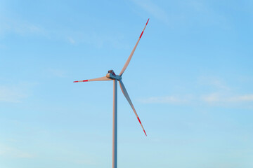 Wind turbine for power generation outdoors with sun and blue sky.
