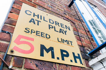 Old sign warning drivers that children are playing in the area, and to adhere to a 5 mph speed limit. - obrazy, fototapety, plakaty