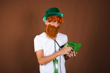 St.Patrick 's Day. Funny guy in a leprechaun costume posing on a brown background.