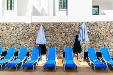 Blue sunloungers on a tiled area at a Spanish hotel.
