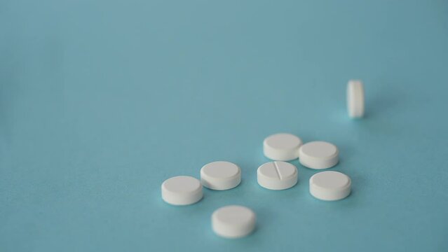 White medical pills or tablets with a bottle on a blue background. Side view of macro with copy space