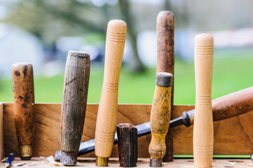 A selection of old woodworking chisels on an outdoor bench - obrazy, fototapety, plakaty