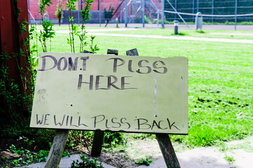 Sign at a public park saying "Don't piss here. We will piss back"
