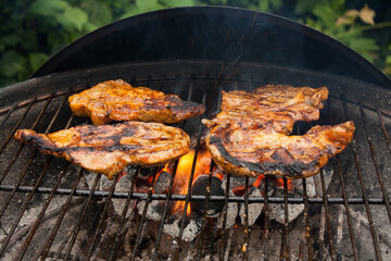 Grilling a juicy steak in the flames of a coal barbecue - obrazy, fototapety, plakaty