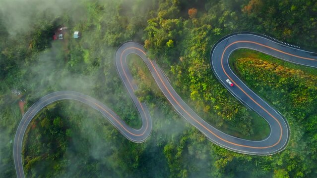 Aerial view of country road in forest morning. Drone shot flying over country road with curved in the mountain with fog. Landmark tourist attractions in Nan Province, Thailand