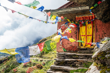 Small Buddhist monastery decorated with multicolored Tibetan prayer flags with mantras on Kothe - Thangnak climbing Mera peak route in Makalu Barun National Park. Peaceful and sacred place photo. - obrazy, fototapety, plakaty