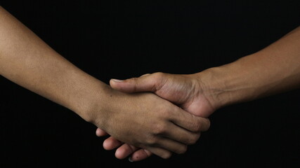 Close up two man shaking hand as agreement on black background.