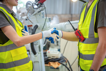 Engineers team mechanic shaking hand in steel factory workshop. Industry robot programming software...