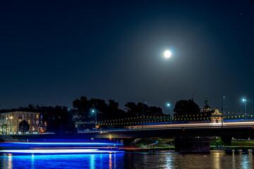 Night lights over the Vistula River in Krakow at the rising of the full moon.