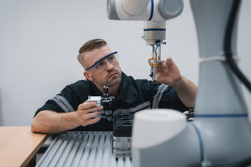 Student engineer Assembling Robotic Arm with computer in Technology Workshop. Service Engineer Holding Robot Controller and Checking Robotic Arm Welding Hardware.