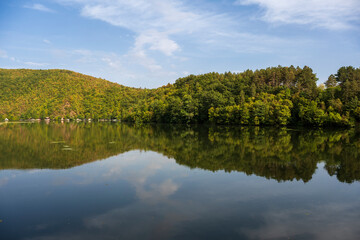 Spring landscape with beautiful clouds in the blue sky. Picturesque view of nature wild lake.  Incredible view on mountains lake. Amazing natural Background.