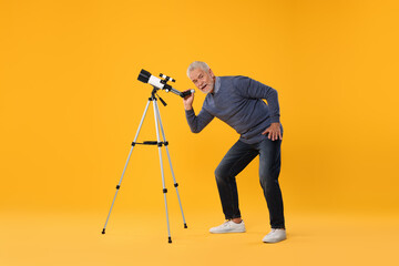 Senior astronomer with telescope on yellow background