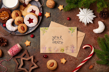 Christmas background with Christmas cookies and milk, letter for Santa from a child, and xmas decorations: Christmas tree, balls, candies, pine cones, stars. Top view