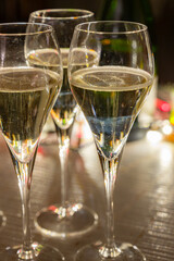 New year party, small bubbles of brut champagne cava or prosecco wine in tulip glasses with garland  lights on background