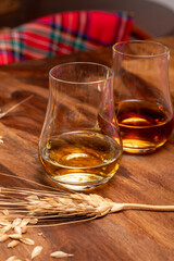 Tasting of different Scotch whiskies strong alcoholic drinks, drum of whiskey and colorful Scotch tartan on background close up