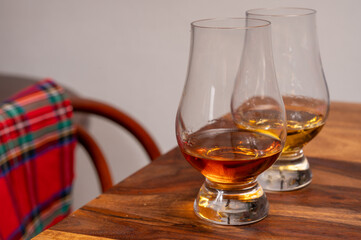 Tasting of different Scotch whiskies strong alcoholic drinks, drum of whiskey and colorful Scotch tartan on background close up